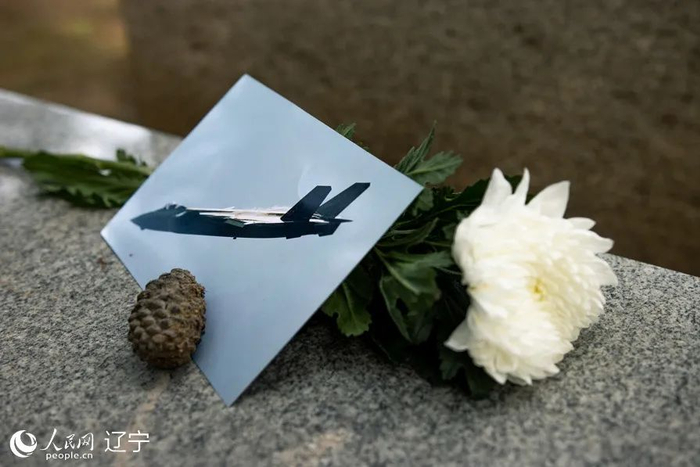 市民送来的“歼-20”照片和一朵白菊花。人民网 邱宇哲摄