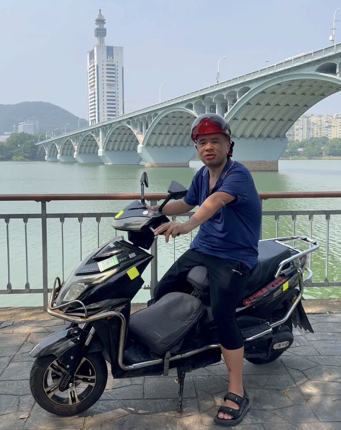 杜杨骑着摩的在橘子洲头景区。受访者供图