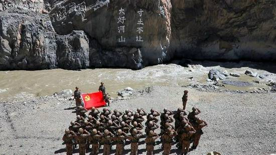 某边防团官兵在“大好河山 寸土不让”标语前举行重温入党誓词仪式（新华社）