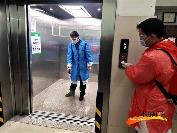 工作人员对超市电梯进行消杀工作。张霞 摄