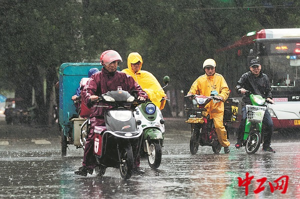 雨天，外卖骑手在北京的一个路口等绿灯。工人日报—中工网记者 王伟伟 摄