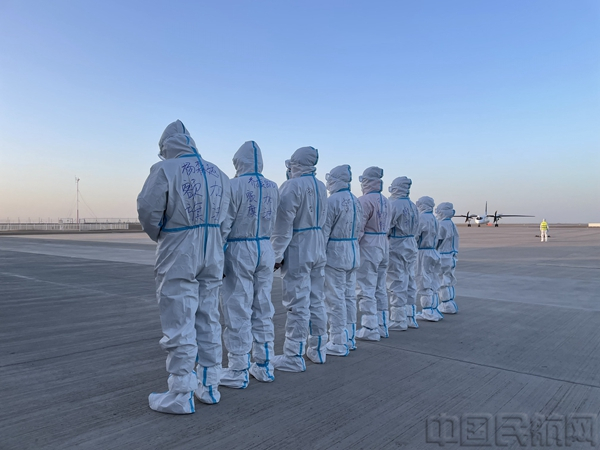 等待包机入位的额济纳机场员工，身着的防护服上写着“额旗加油”