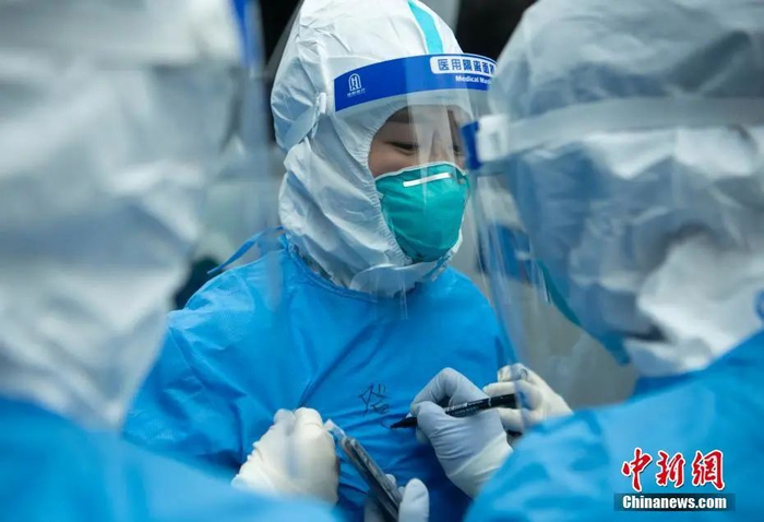 资料图：四川成都，即将进入患者居住小区的医护人员在防护服上写上自己的名字和单位。中新社记者 刘忠俊 摄