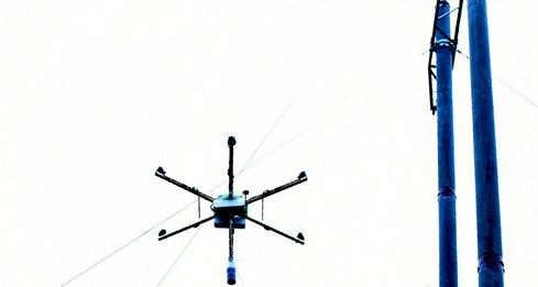 △施工人员使用无人机“穿针引线”架设群山高压线路。