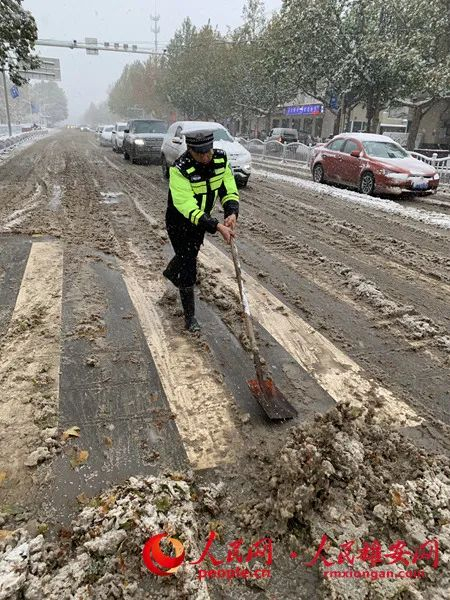 雄县交警在风雪中清理道路积雪。陈达摄