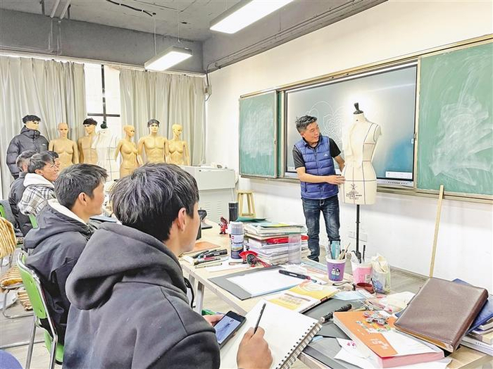 图为外聘老师在给该校服装专业学生讲授制衣设计流程。