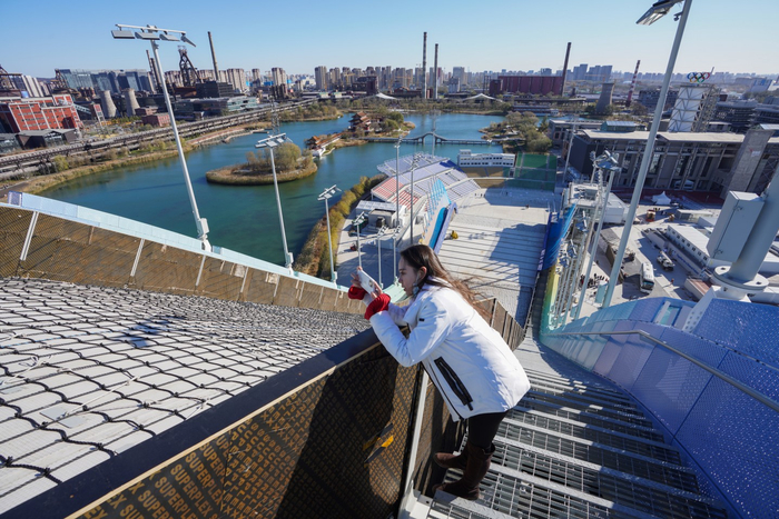 工作人员在首钢滑雪大跳台前拍照留念。新京报记者 陶冉 摄