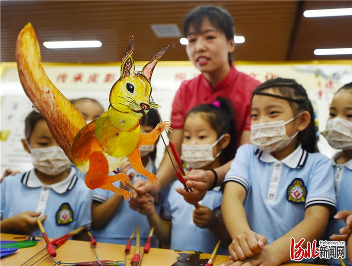 6月12日，沙河皮影戏艺人在为小朋友演示皮影戏。