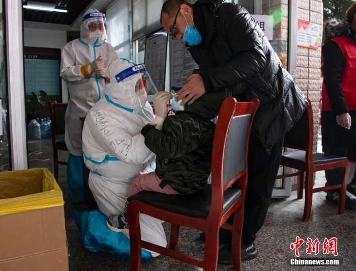 图为苏倩在一小区俯身跪地为一名小朋友采样。中新社记者 侯宇 摄