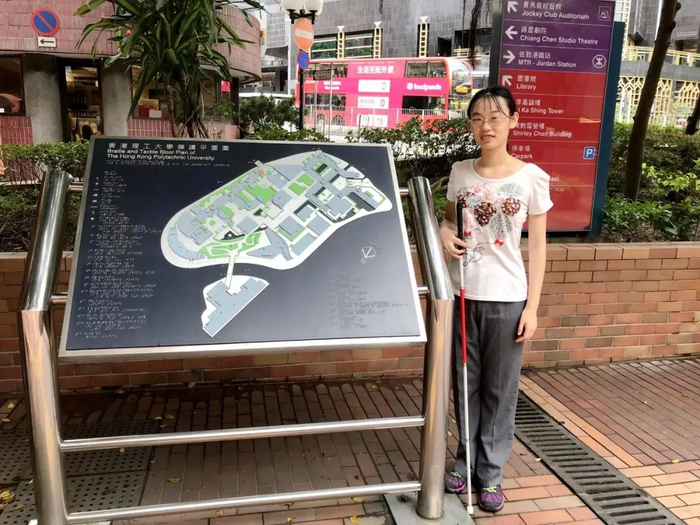 ▲ 2019年9月，朱苓君在香港理工大学校门口的学校盲文地图指引前留影