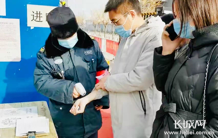 小区保安人员对进入小区人员进行测温。图片由邢台日报提供。