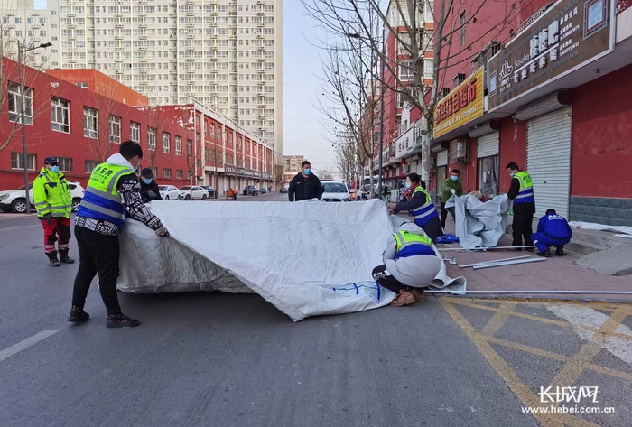 中国人保财险石家庄赵县支公司党员志愿者李诺（左4）在协助搭建帐篷。