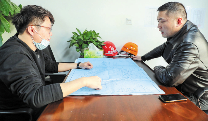 罗剑骁（右）在项目工地办公室与同事探讨施工进展