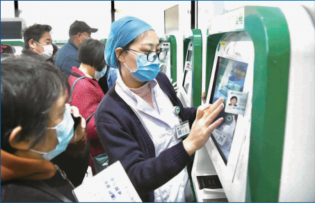 图说：浦东医院门诊大厅里医务人员帮助老人操作自助挂号机 新民晚报记者 徐程/摄
