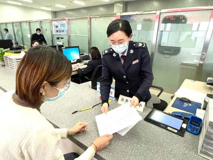 图为国家税务总局平度市税务局干部为纳税人办理异地房产契税缴纳业务。