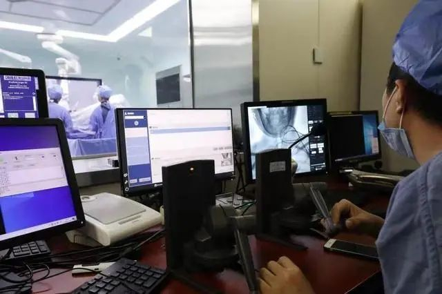 手术医生在机器人主控端，通过显示屏的引导，操控两个手柄进行手术。北京天坛医院岳朴供图