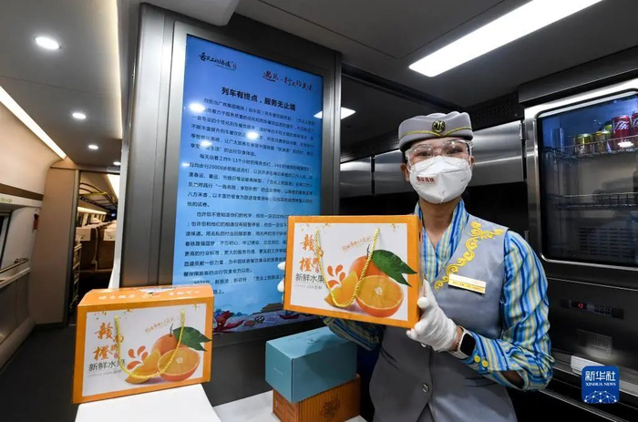 ▲12月10日，深圳北站开往南昌西站的首班列车上，乘务员展示车上售卖的江西特产。新华社记者 毛思倩 摄