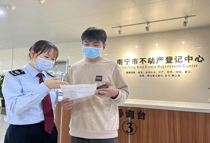 图为南宁市税务局工作人员指导纳税人通过不动产登记和税费缴纳“一网通办”，完成不动产登记缴税业务。梁梦婕/摄