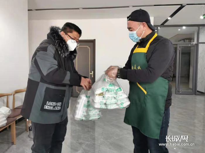 赵魏将饭菜送到抗疫工作人员的手里。吴长保 供图