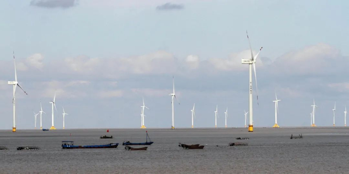 ▲渔船驶过江苏南通的一个风电场。图片来源：Alamy
