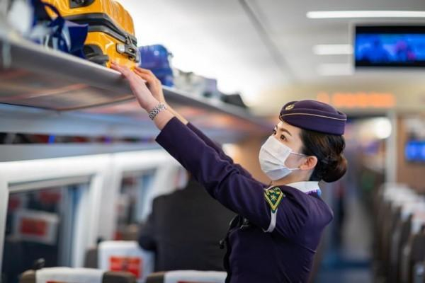 图说：上海客运段值乘的G22次列车上，乘务人员在整理行李架上的物品。 李忱 摄