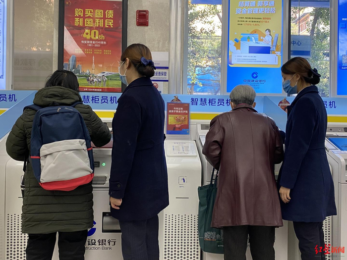 在某银行大厅内，工作人员正在教老年客户使用银行智能柜员机 红星资本局摄