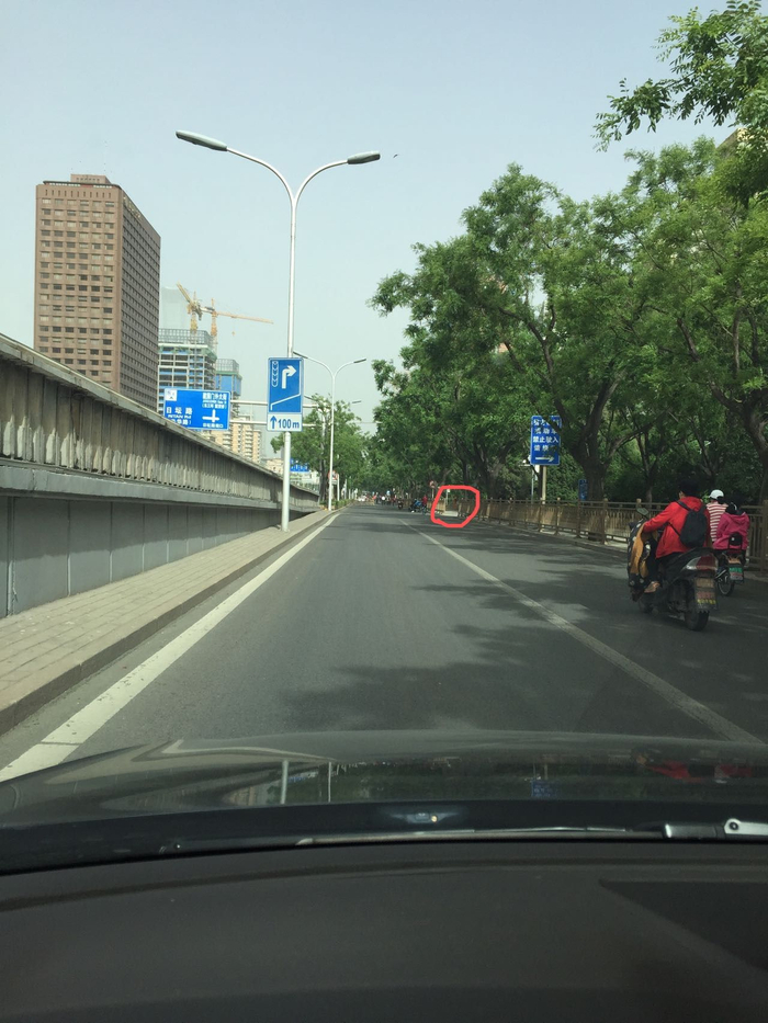 ▲张先生提供的其今年春季在建国门桥东辅路行驶时的画面，红圈处为右转路口，画面左侧的“直行100米进入右转专用道”标志是对主路车辆进行提示用的。 受访者供图