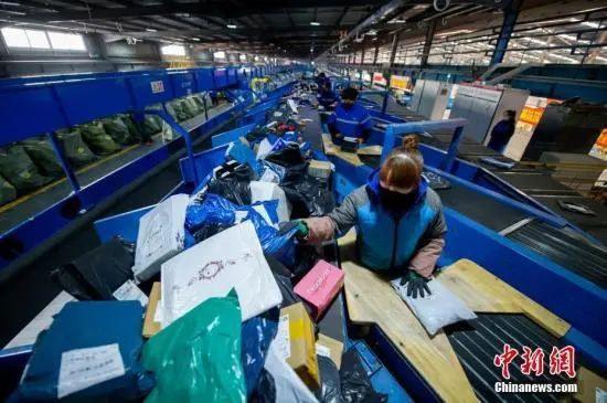 资料图：在中通快递山西转运中心，员工戴着口罩分拣包裹。中新社记者 韦亮 摄