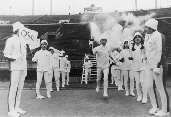 ▲日本滑冰运动员Tomoo Kurosawa手持火炬抵达东京奥林匹克体育场