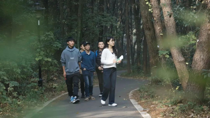 ▲姚昱浓给同学讲解如何辨认植物（戴壮 摄）