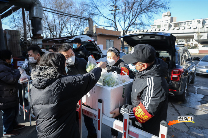 居民在小区门口挑选新鲜蔬菜，每个袋子上，社区志愿者都写上了购买时的菜价。长城网记者 刘潇 摄