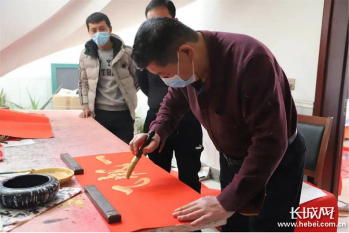 李清涛（右一）在书写新春对联。通讯员 刘晓霞 供图