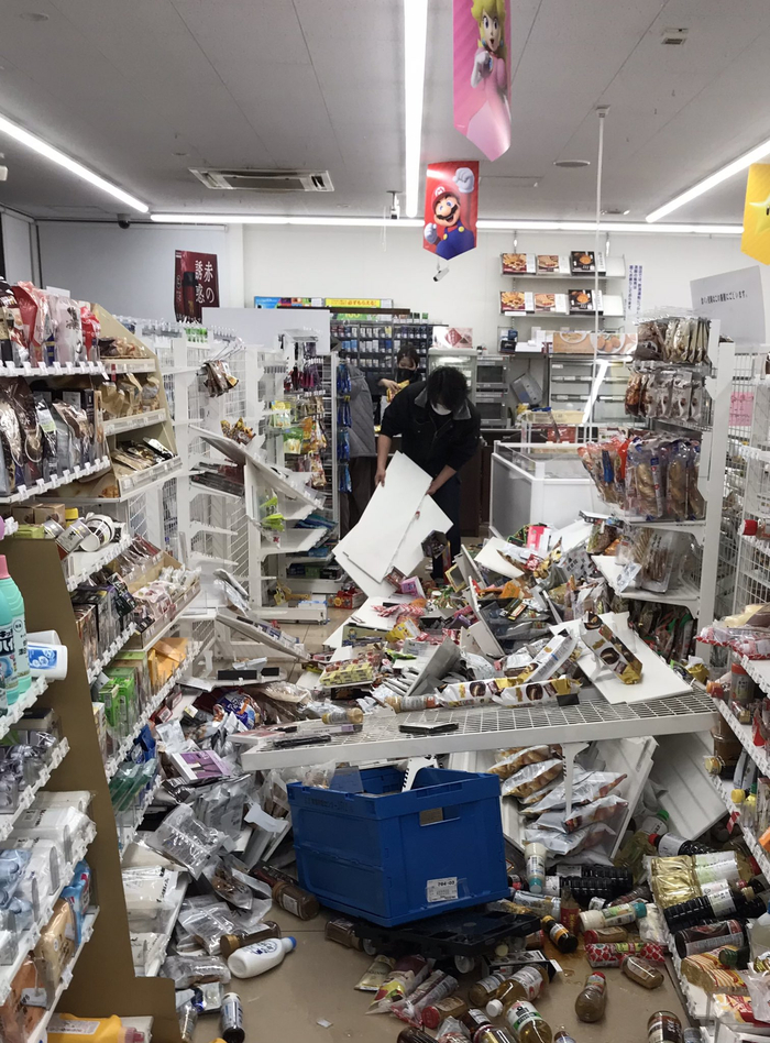 福岛市一家便利店店员正在收拾地震后散落一地的货物。