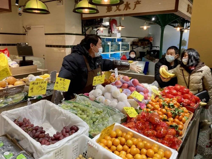 翁老板在水果摊上与顾客交谈