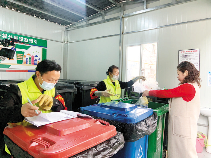 映月花园小区居民在监督员引导下投放垃圾