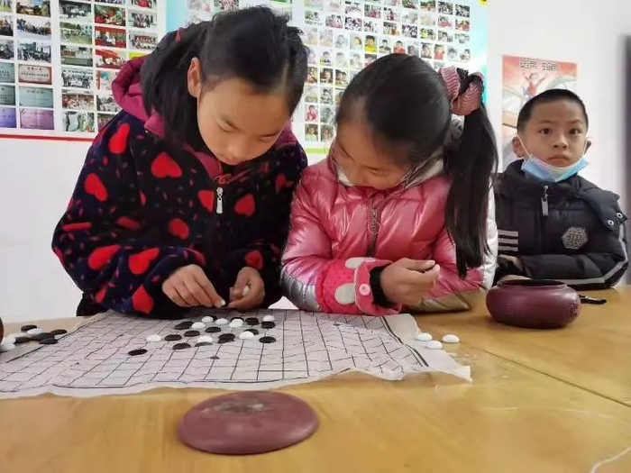 小江（左一）在和村里小伙伴下五子棋。新华社记者陈尚营 摄