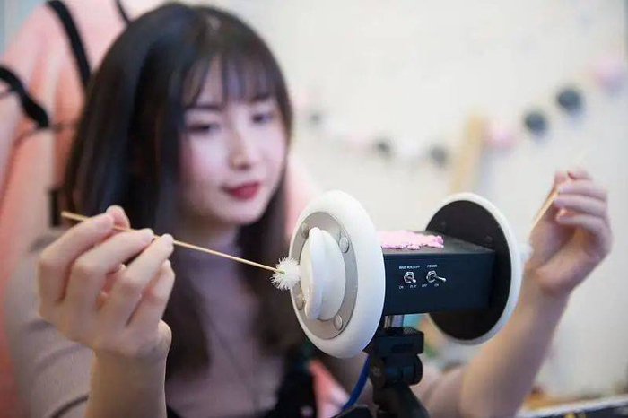 ASMR主播把鹅毛棒放进“模拟耳朵”轻轻掏耳。图片：CFP
