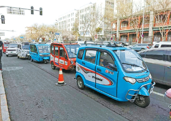 南新华街西侧，大量老年代步车停靠等候接孩子放学。