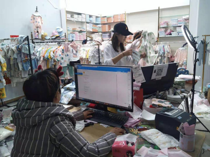 直播中的主播，一旁的工作人员正监测实时直播数据。刘畅/摄