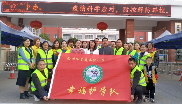 广西钦州市皇庭实验小学“护学岗”部分家长志愿者与学校老师合影（学校供图）