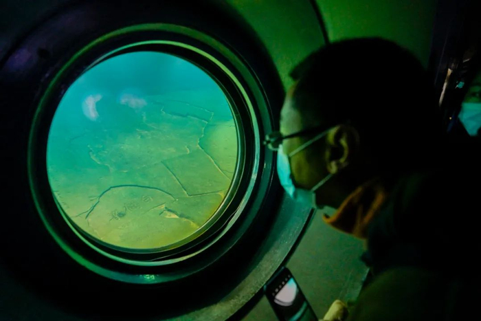 由于三峡工程的建设，白鹤梁淹没在水中，为了保护这处文化遗产，建立了水下博物馆。图为近日，一位观众通过观景窗清晰观看保护罩内静卧水中的白鹤梁题刻。（新华社记者 刘潺 摄）