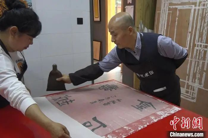 高丘波正在给字画刷浆装裱。　张俊　摄