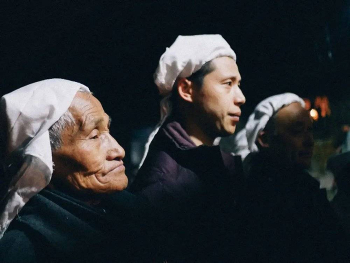 逝去老人的亲人，他们戴着白色的孝布。