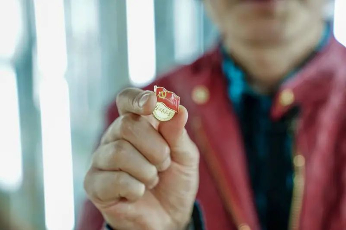 陈加枢手持金乡徽章厂生产的党徽。