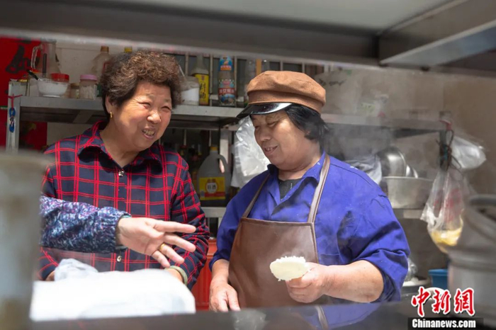 熊庚香（右）一边给病人家属打饭一边表示，自己和很多来这里做饭的人都成了朋友。 刘力鑫 摄