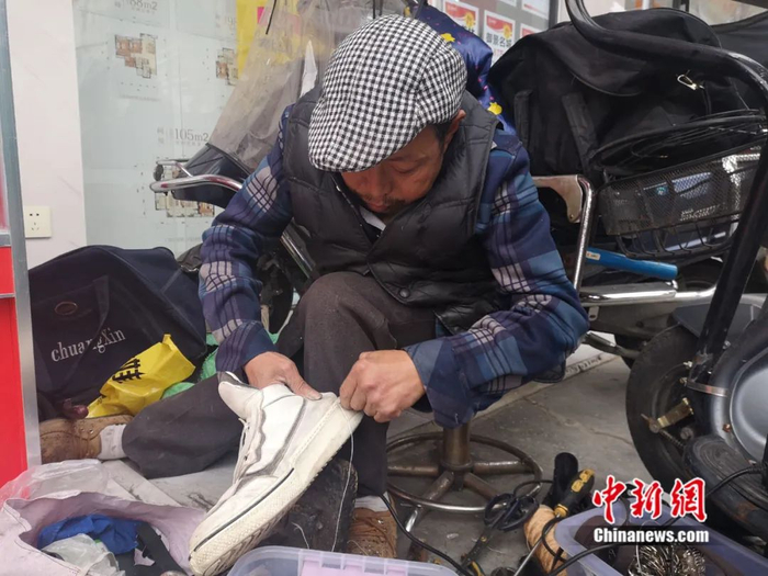白朝平正在给鞋穿线。杨勇 摄