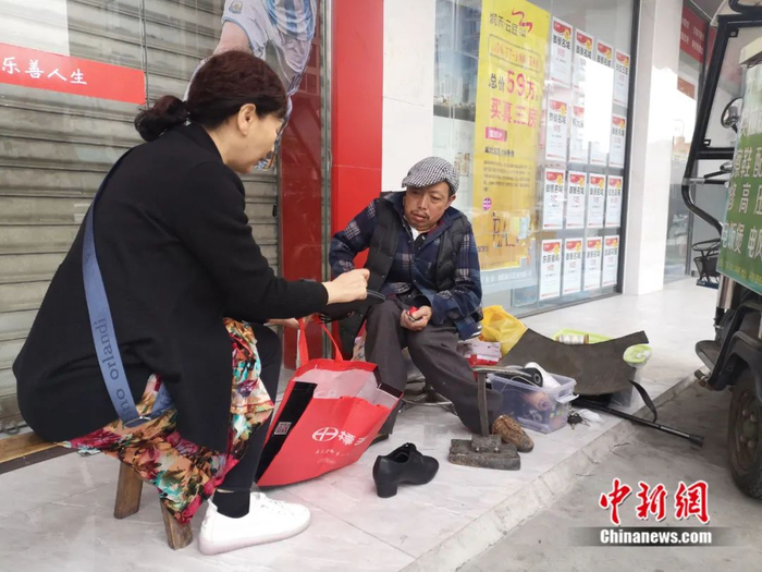 顾客向白朝平展示出需要修补的鞋底。杨勇 摄