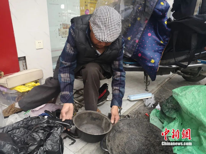 白朝平查看需要修补的锅。杨勇 摄