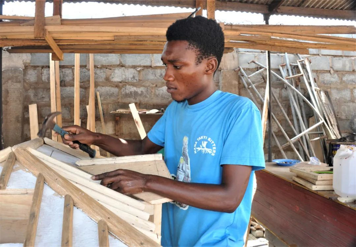 ▲3月23日，在加纳首都阿克拉主城区一家棺材铺里，一名年轻工匠在制作一副房屋造型的棺材。新华社发