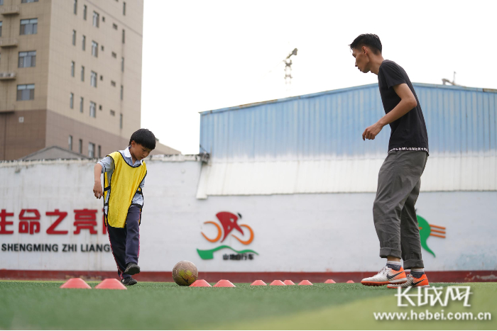 邢台市弘毅小学课后服务老师正在指导学生练习足球。长城网记者 郭硕 摄